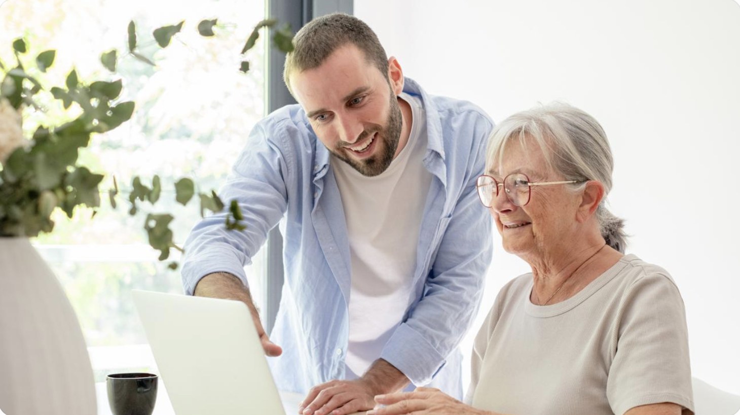 Junger Mann hilft einer älteren Frau am Laptop
